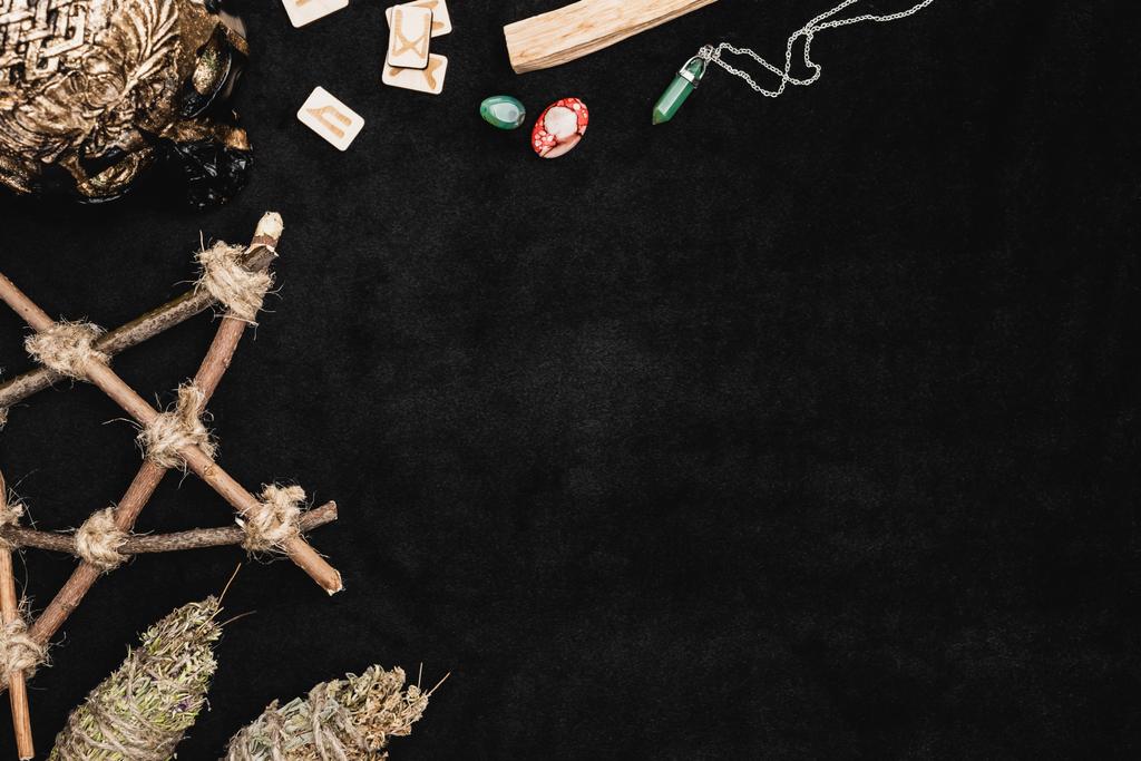 vue de dessus des runes près des amulettes, des cristaux et du crâne vaudou sur le noir - Photo, image