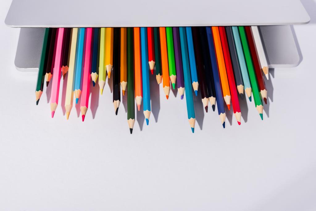 crayons de couleur dans un ordinateur portable moderne sur fond blanc - Photo, image