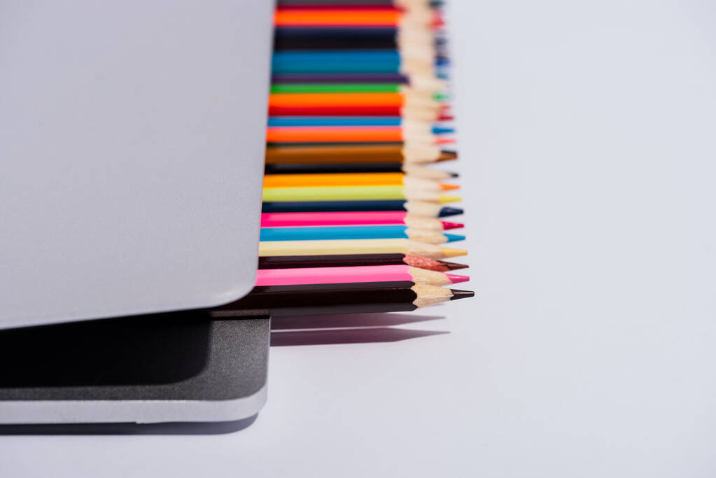 現代のノートパソコンにおける白い背景の色鉛筆の選択的焦点 ロイヤリティフリー写真 画像素材