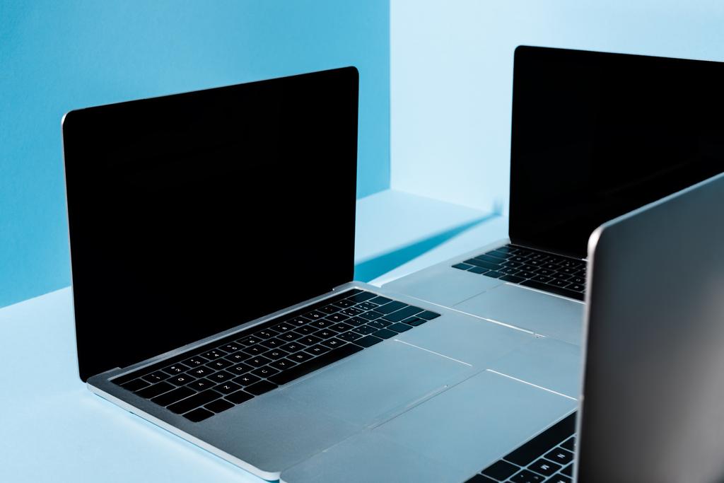 σύγχρονοι φορητοί υπολογιστές με λευκές οθόνες σε μπλε φόντο - Φωτογραφία, εικόνα