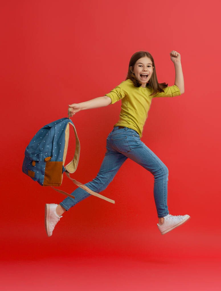 Zurück zur Schule und eine glückliche Zeit! Nettes fleißiges Kind joggt auf farbigem Papier Wandhintergrund. Kind mit Rucksack. Mädchen bereit zum Studium. - Foto, Bild
