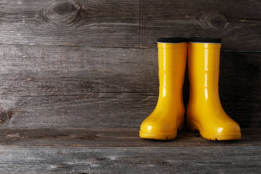 Yellow rubber boots on vintage wooden background with  copy space. - Photo, Image