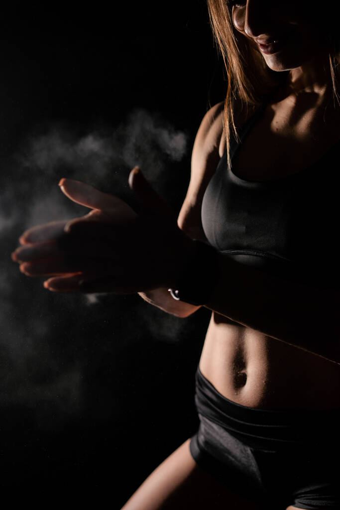 Close up girl shows sports stomach. Healthy fitness and eating lifestyle concept. Fitness sporty woman showing her well trained body, isolated over black background. - Photo, Image