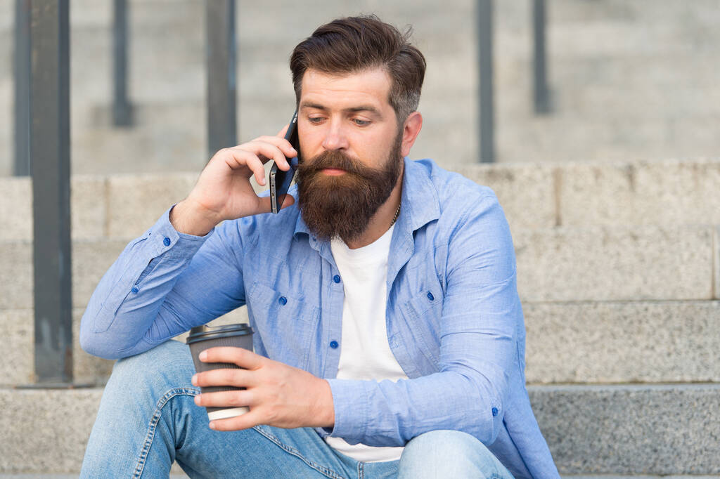 Κινητή ζωή. Hipster πίνουν καφέ μιλώντας στο κινητό τηλέφωνο σε εξωτερικούς χώρους. Κινητή επικοινωνία. Ζεστό φλιτζάνι. Καφές πακέτο. Νέα τεχνολογία. Κινητή συσκευή. 4G. 3G. Σύγχρονος τρόπος ζωής - Φωτογραφία, εικόνα