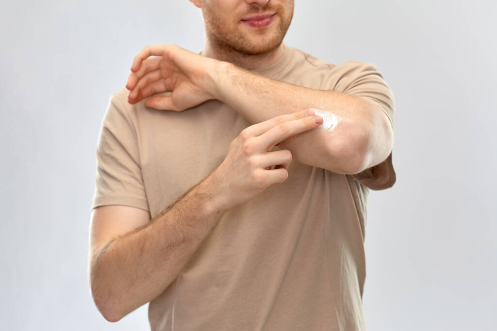 młody człowiek stosujący leki przeciwbólowe na łokieć - Zdjęcie, obraz