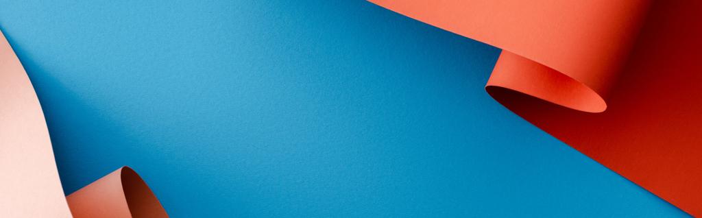 oranje kleurrijke papieren wervelingen op blauwe achtergrond, panoramisch schot - Foto, afbeelding