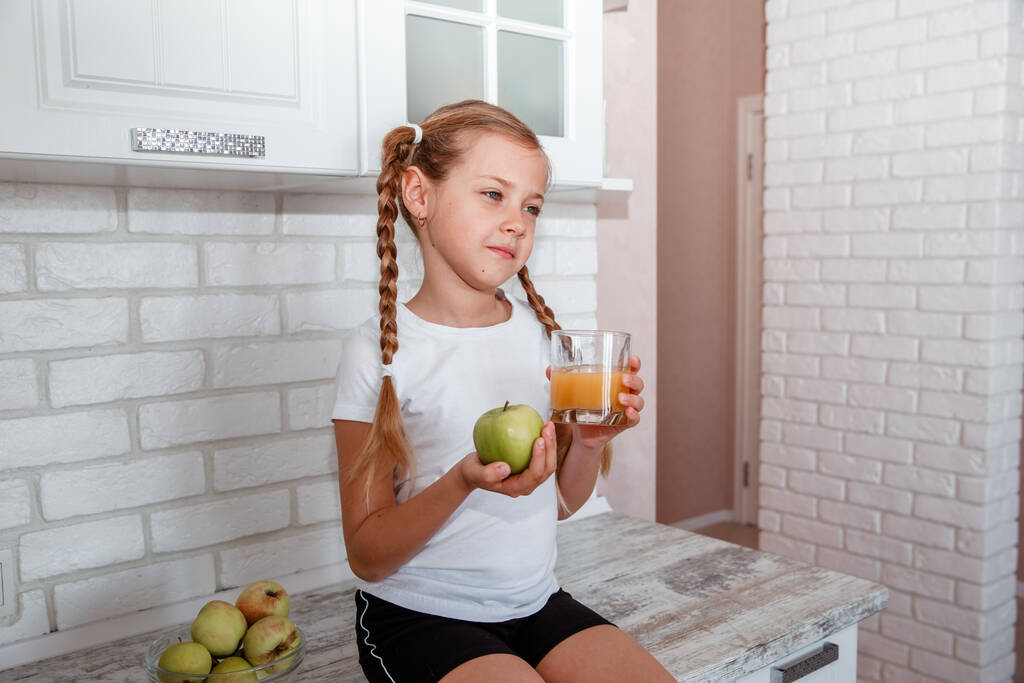 A menina guarda uma maçã e um copo de suco - Foto, Imagem