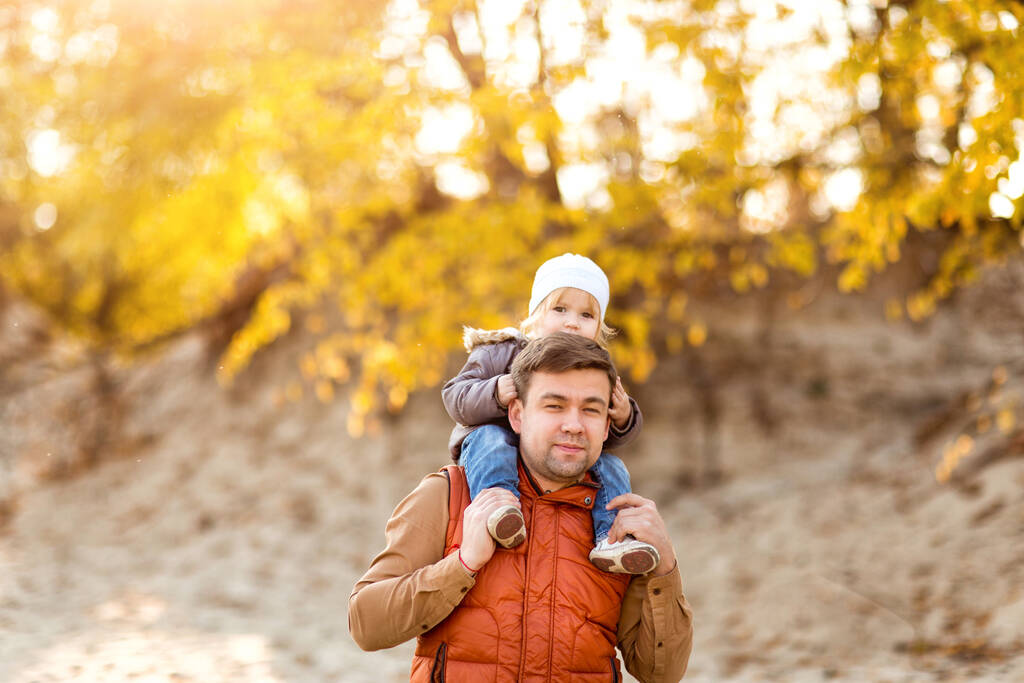 Menina sentada nos ombros do pai no passeio no outono. fim de semana familiar na natureza
. - Foto, Imagem