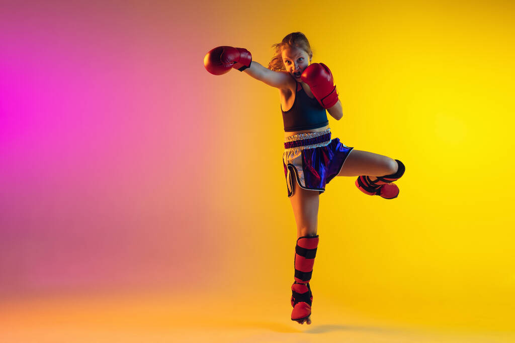 Kis kaukázusi női kick boxer képzés gradiens háttér neon fény, aktív és kifejező - Fotó, kép