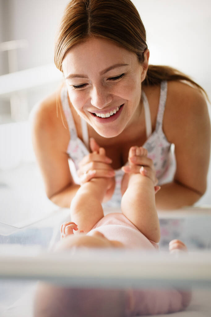 Güzel, sevgi dolu bir annenin portresi ilk maçlarını yatak odasında bebeğiyle oynuyor. - Fotoğraf, Görsel