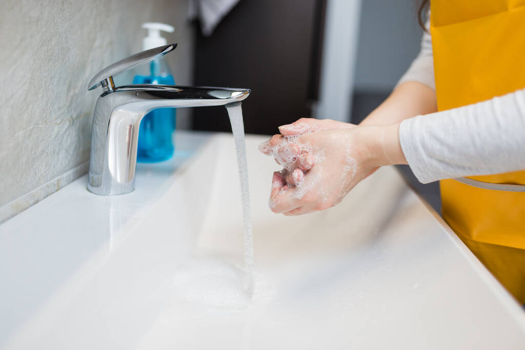 Πλένετε τα χέρια κάτω από τη βρύση ή τη βρύση. Υγιεινή έννοια λεπτομέρεια. Όμορφο χέρι και ρεύμα νερού στο μπάνιο. Νέος σύγχρονος καθαρισμός λεκάνης. - Φωτογραφία, εικόνα