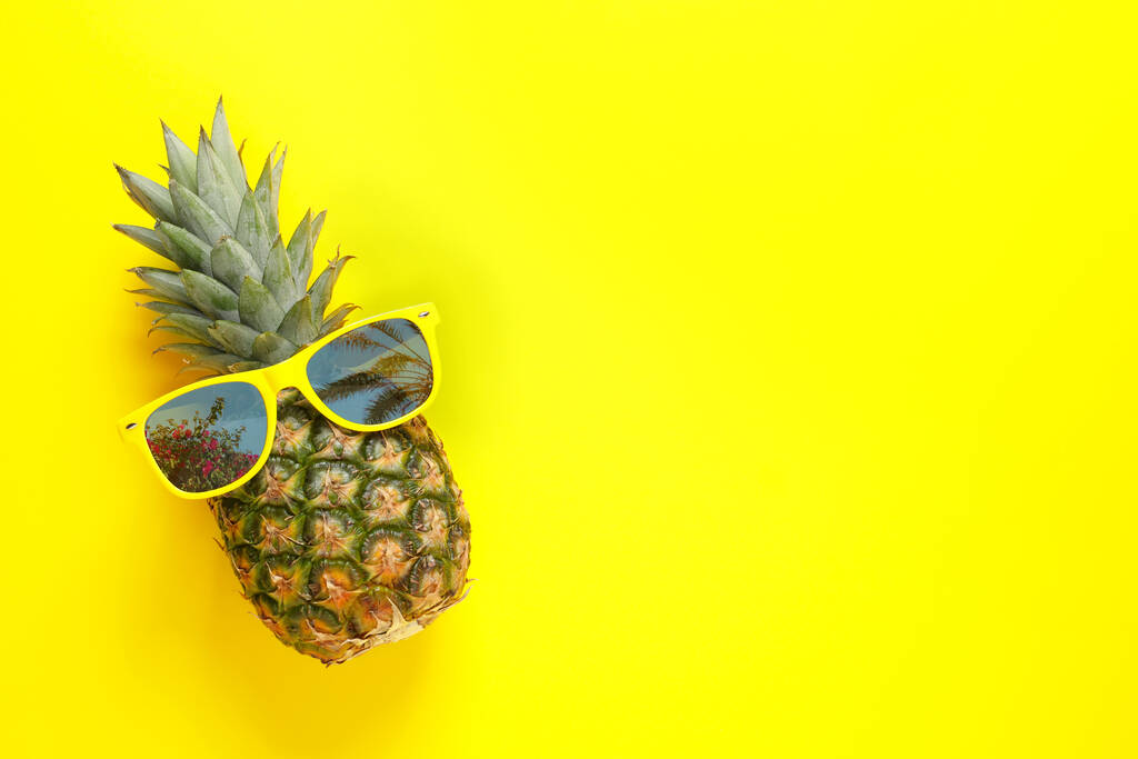 Ananas und Sonnenbrille mit Reflexion von Palmen auf gelbem Hintergrund, Draufsicht. Raum für Text - Foto, Bild
