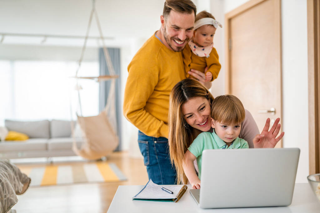 Ευτυχισμένη οικογένεια κουβεντιάζοντας με τον υπολογιστή μαζί στο σπίτι - Φωτογραφία, εικόνα
