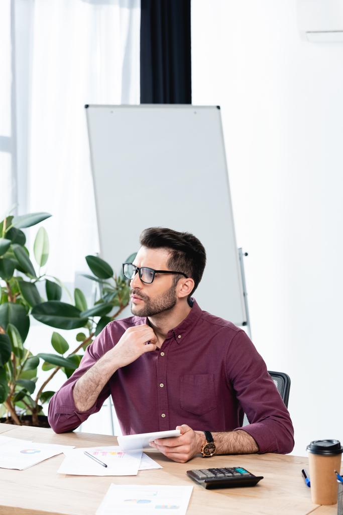 若いビジネスマンがオフィスに座って夏の暑さに苦しみながらシャツに触れると - 写真・画像