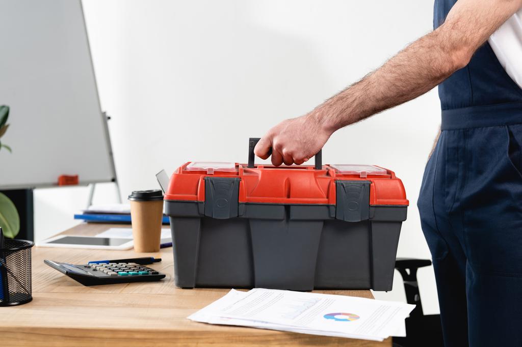 обрезанный вид ремонтника с ящиком инструментов на рабочем столе с бумагами и кофе, чтобы пойти
 - Фото, изображение