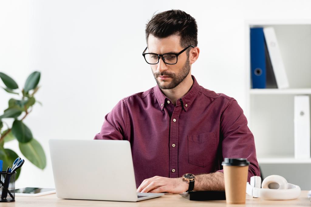 συγκεντρωμένος επιχειρηματίας δακτυλογράφηση σε φορητό υπολογιστή στο γραφείο  - Φωτογραφία, εικόνα