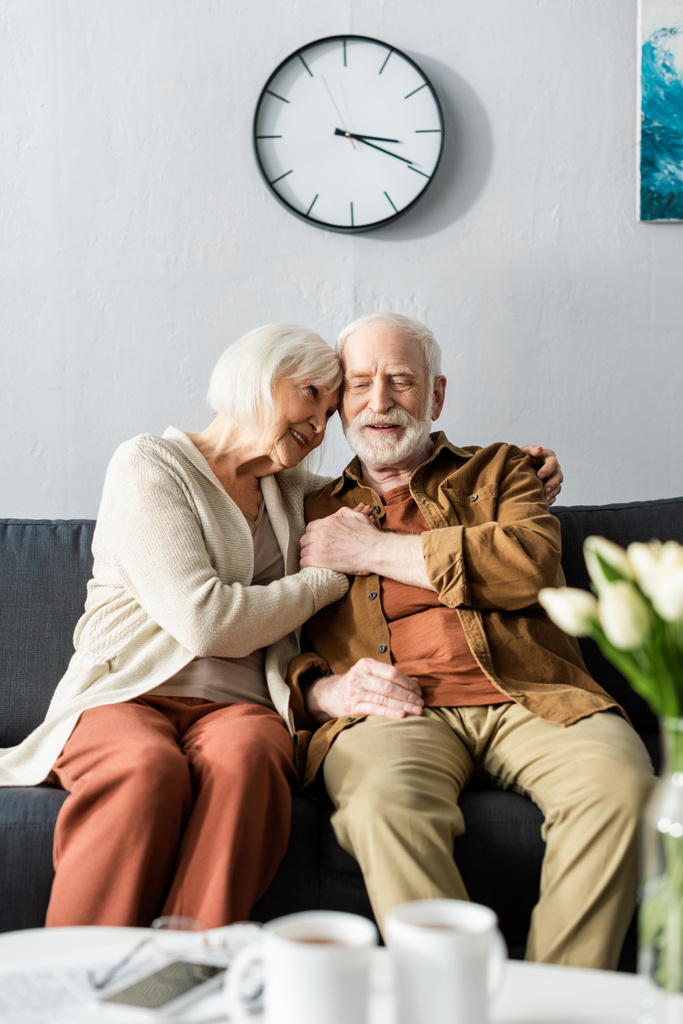 Selektiver Fokus glücklicher Senioren, die auf dem Sofa sitzen und Händchen halten - Foto, Bild