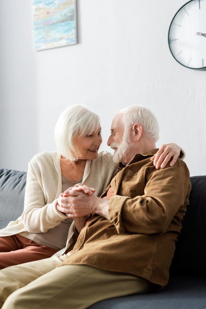 felice coppia di anziani che si abbracciano e si tengono per mano mentre si guardano - Foto, immagini