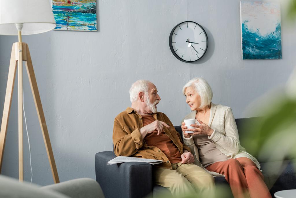 селективное внимание счастливой пожилой пары, разговаривающей, сидя дома на диване
 - Фото, изображение
