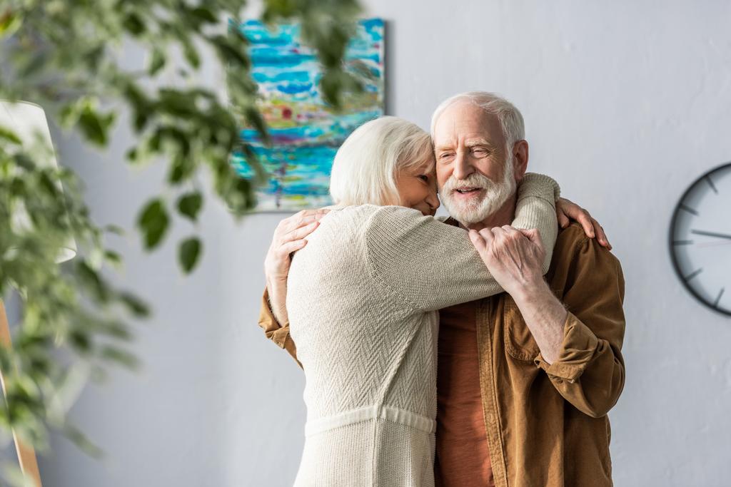 selectieve focus van gelukkig senior man knuffelen glimlachende vrouw - Foto, afbeelding