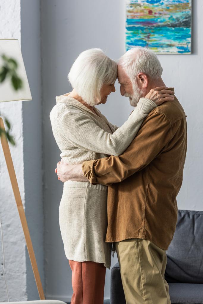 боковой вид счастливой пожилой пары, которая улыбается, стоя лицом к лицу
 - Фото, изображение