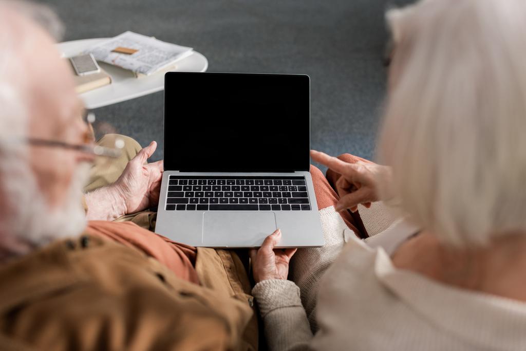 селективная фокусировка пожилой пары с помощью ноутбука с чистым экраном, вид сверху
 - Фото, изображение
