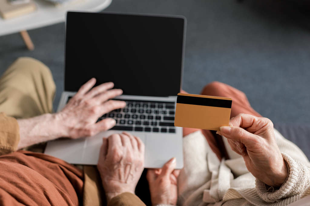 Üst düzey bir adamın elinde kredi kartı olan, karısının yanında boş ekranlı aptop kullandığına dair kırpılmış görüntü. - Fotoğraf, Görsel