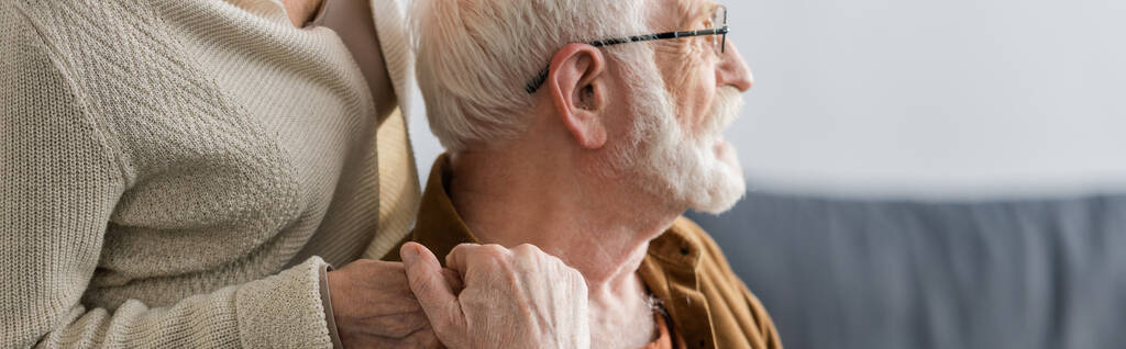 oříznutý pohled na ženu držící za ruku staršího manžela, horizontální obraz - Fotografie, Obrázek