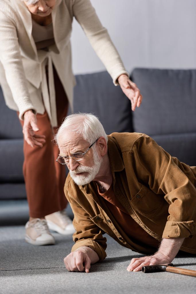 przycięty widok kobiety pomaga upadłemu starszemu mężowi wstać z podłogi - Zdjęcie, obraz
