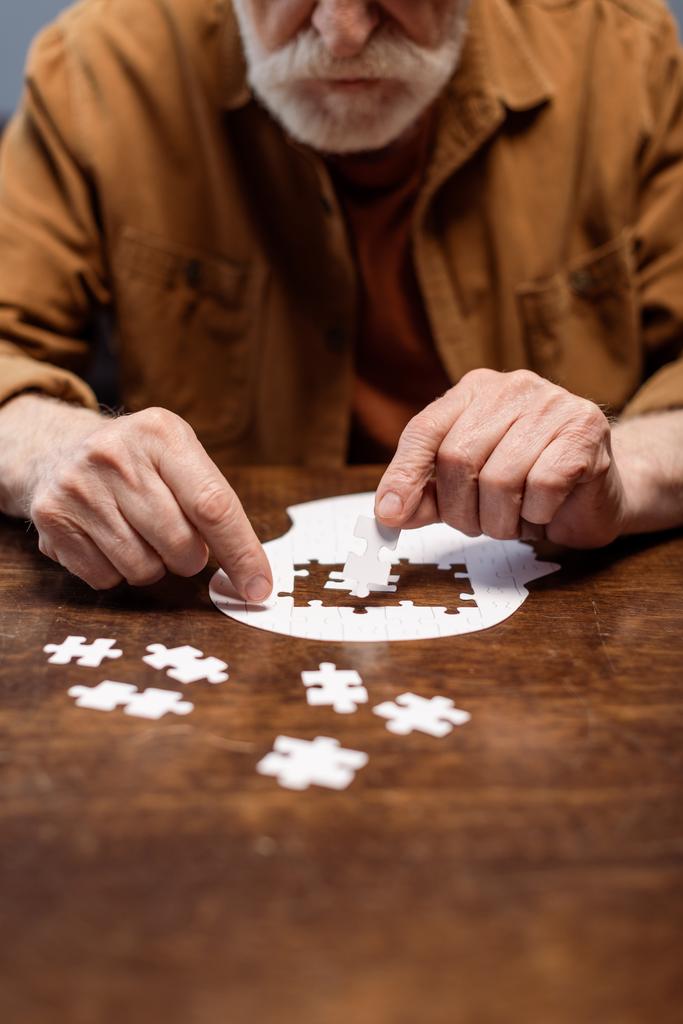 Ausgeschnittene Ansicht eines älteren Mannes, der Puzzle für Demenz-Rehabilitation spielt - Foto, Bild