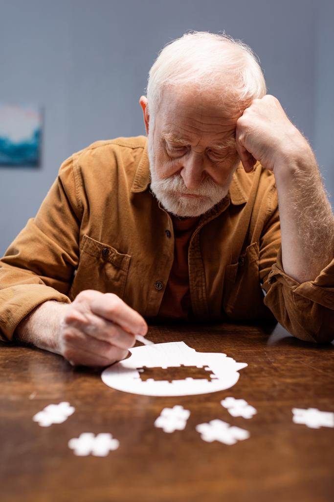 selective focus of senior man collecting jigsaw puzzle as dementia therapy - Photo, Image