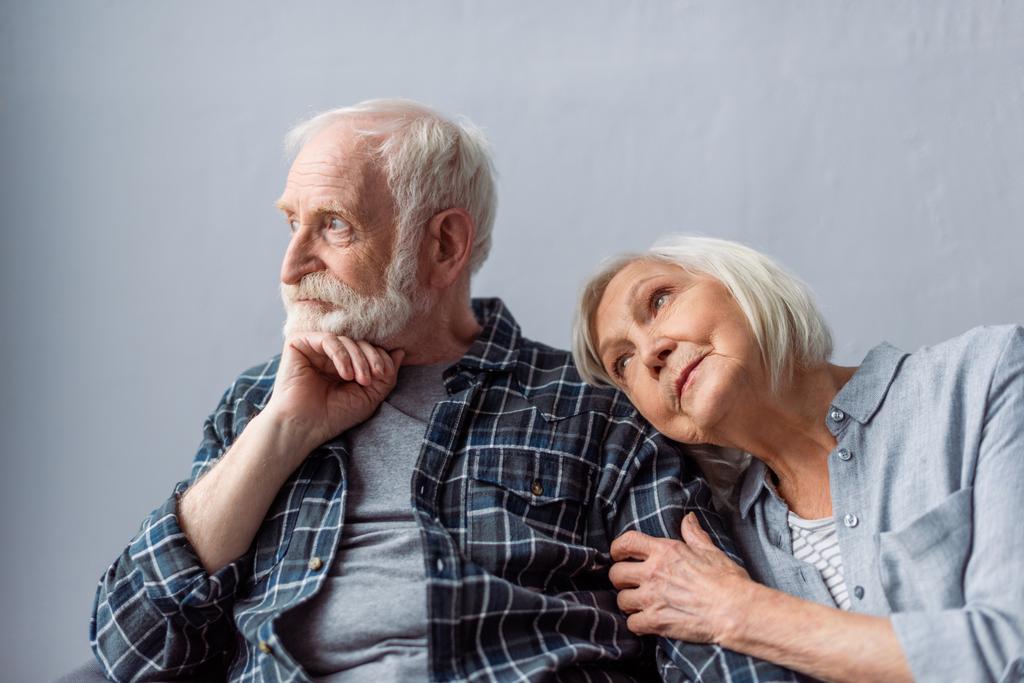 verträumte Seniorin stützt sich auf Schulter eines nachdenklichen Ehemannes, der wegschaut - Foto, Bild