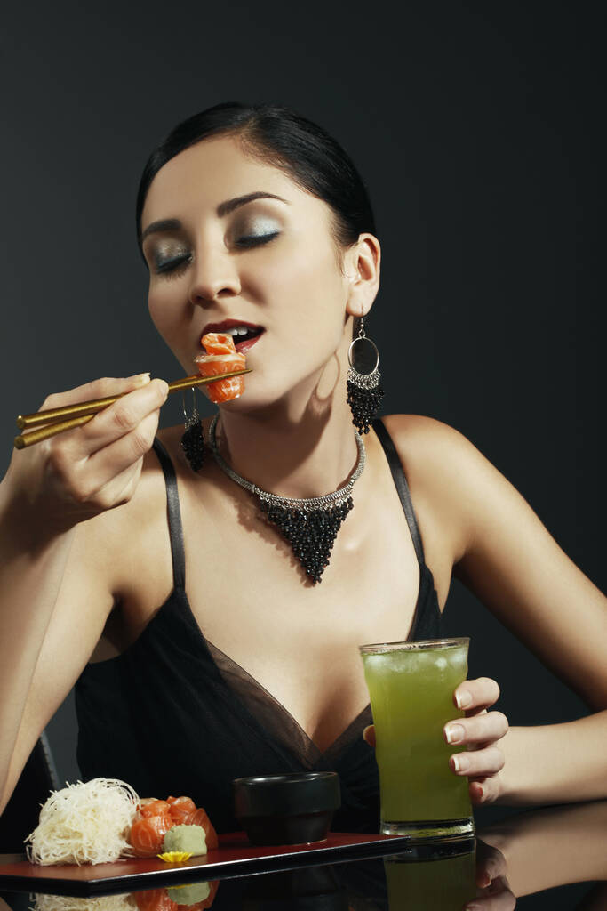 Femme mangeant du saumon sashimi avec du thé vert froid - Photo, image