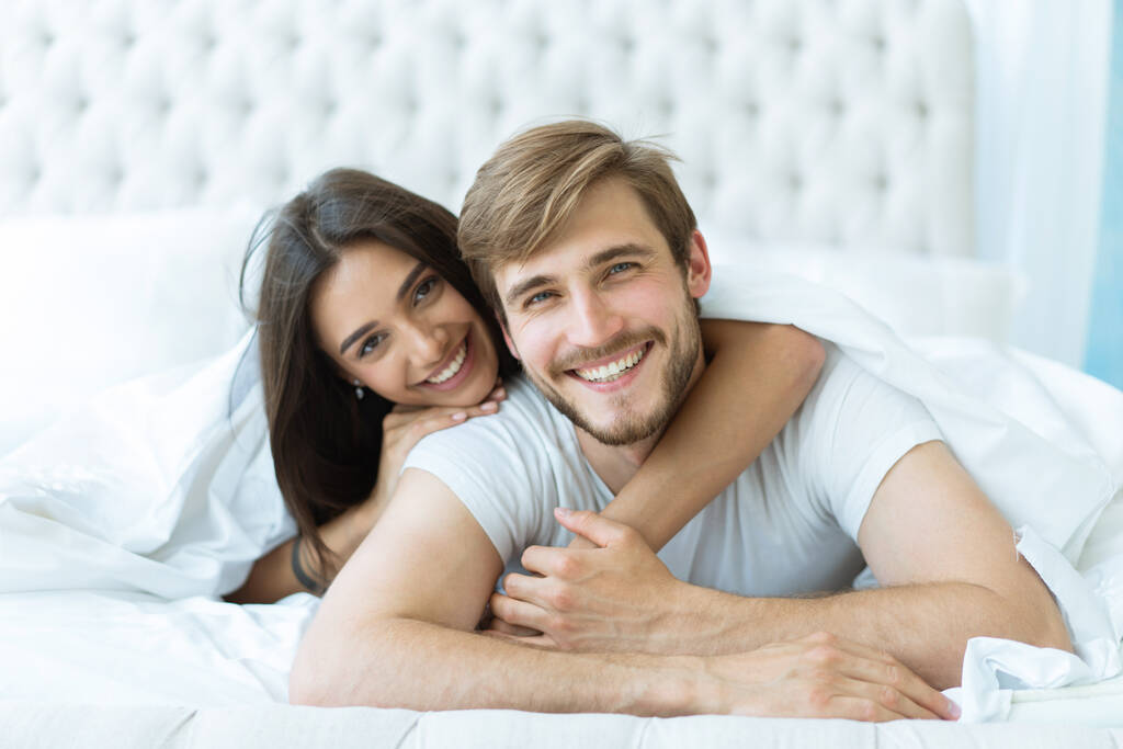 若い幸せなカップルがベッドで一緒に横たわっている. - 写真・画像