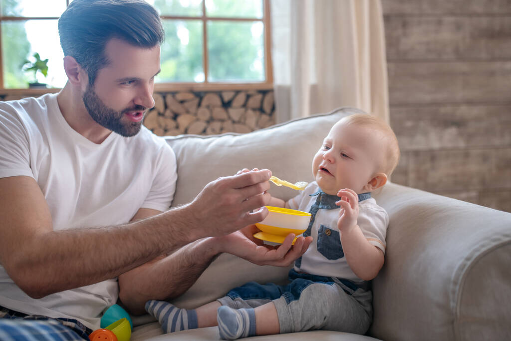 Junger Vater füttert das Baby und lächelt - Foto, Bild