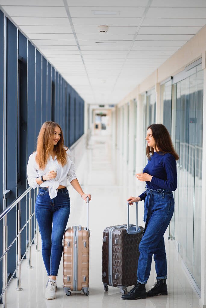 Two women at the airport go on a plane. girlfriends at the airport with suitcases - Photo, Image