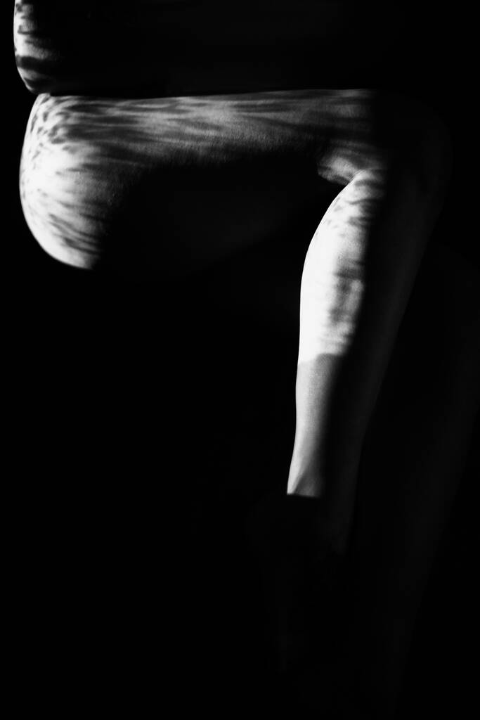 Siyah beyaz desenli ve yansıması olan çıplak kadın vücudu. Projektörle siyah-beyaz fotoğraf oluşturuldu - Fotoğraf, Görsel