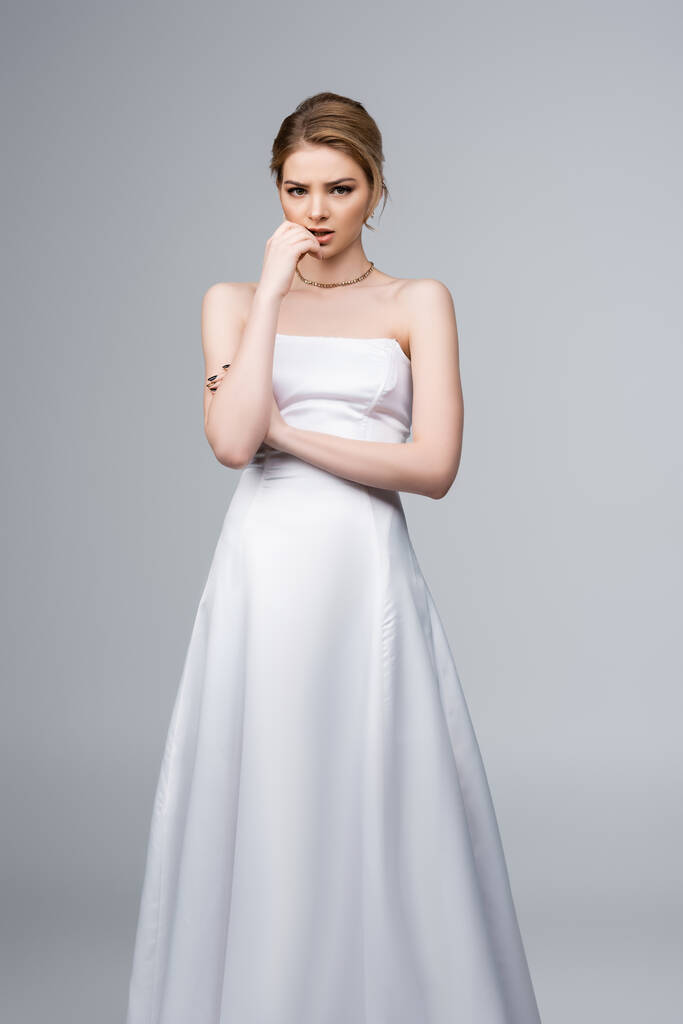 беспокойная невеста в белом свадебном платье трогательное лицо изолировано на сером
  - Фото, изображение