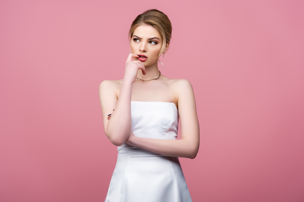 novia pensativa en vestido de novia blanco mirando hacia otro lado aislado en rosa
  - Foto, imagen