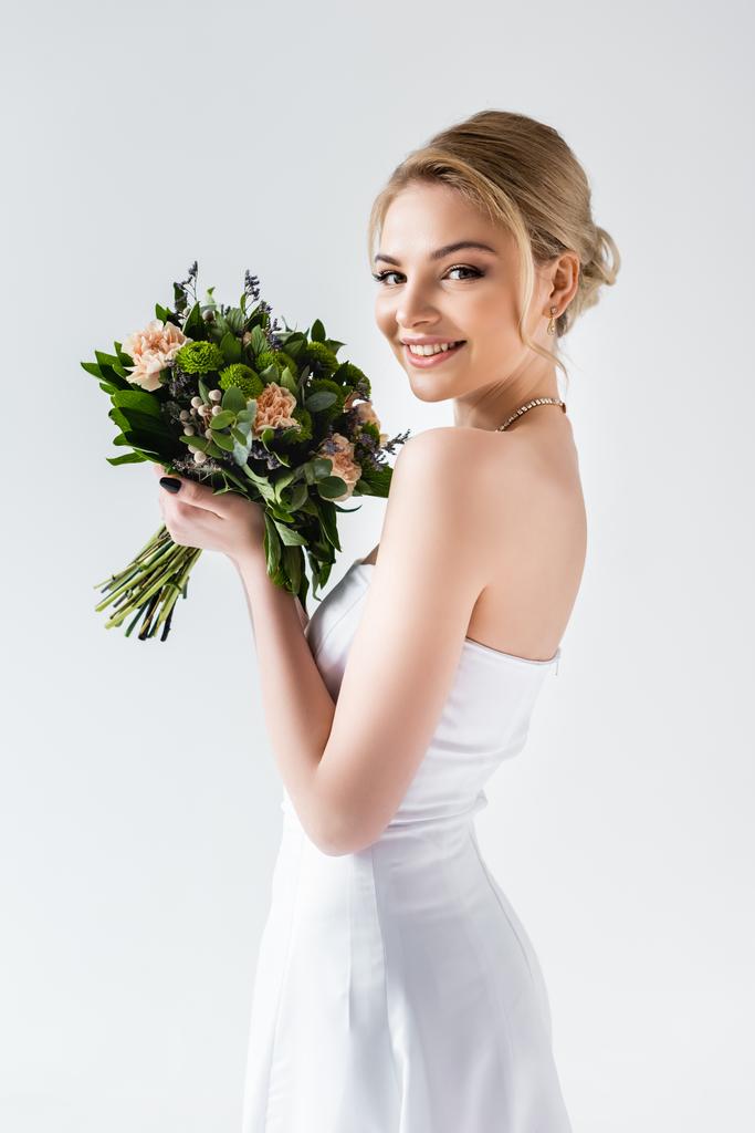 gelukkig bruid in elegante trouwjurk met bloemen geïsoleerd op wit  - Foto, afbeelding