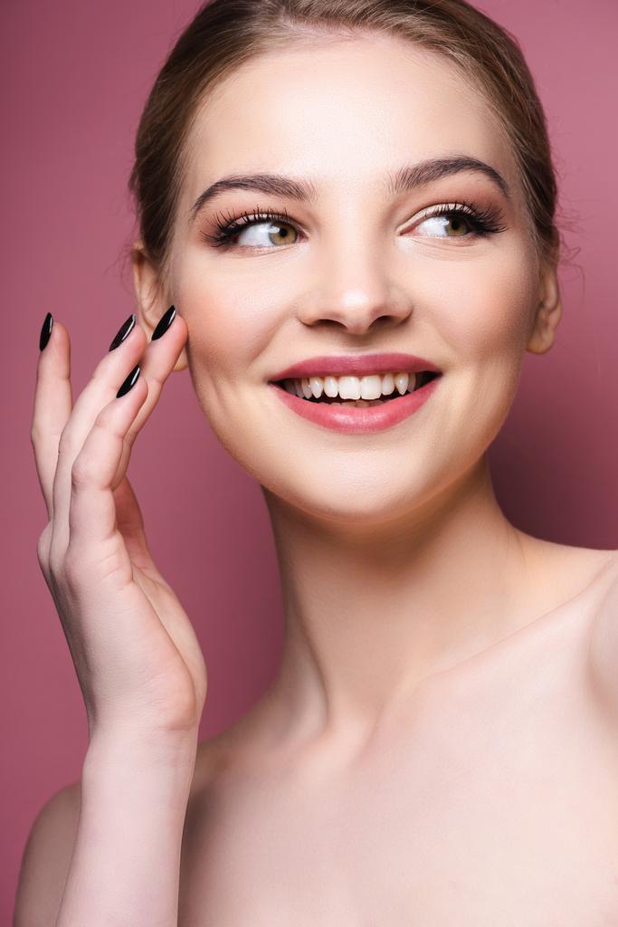 pretty woman with eye shadow and lipstick touching face and smiling on pink  - Photo, Image