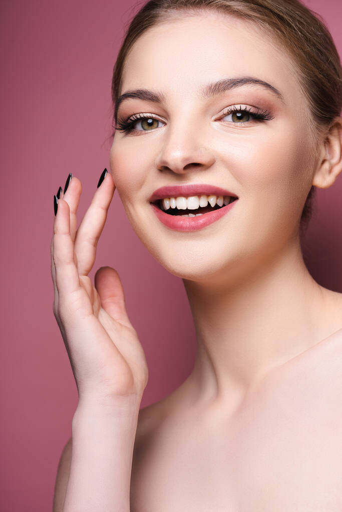 alaston nuori nainen luomiväri ja huulipuna koskettaa kasvoja ja hymyilee vaaleanpunainen  - Valokuva, kuva