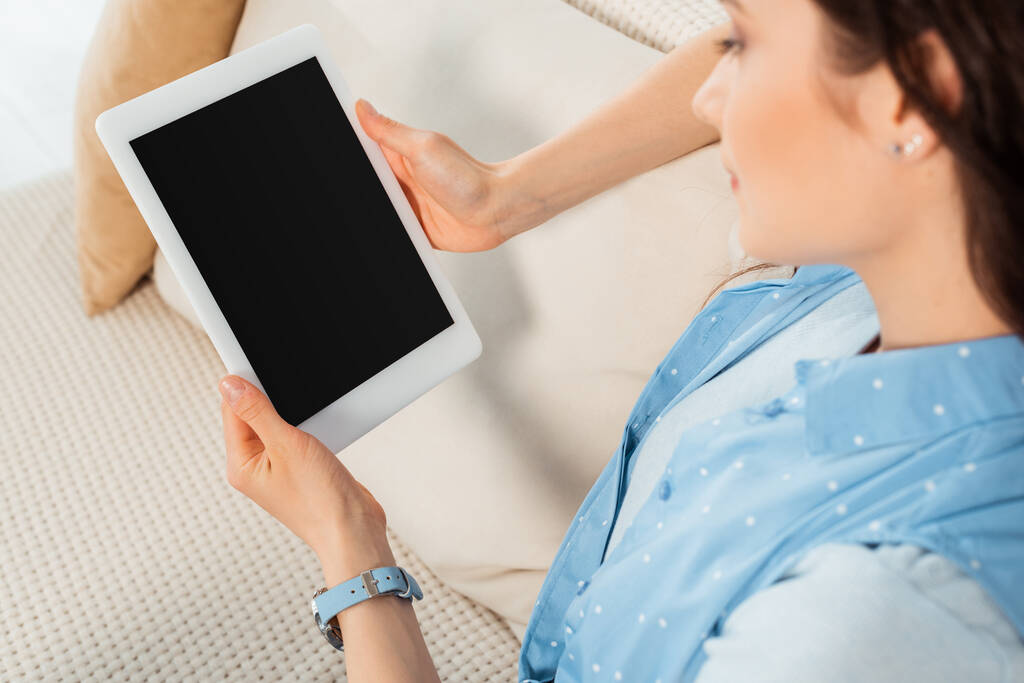 Вибірковий фокус молодої жінки, що тримає цифровий планшет з порожнім екраном на дивані
  - Фото, зображення