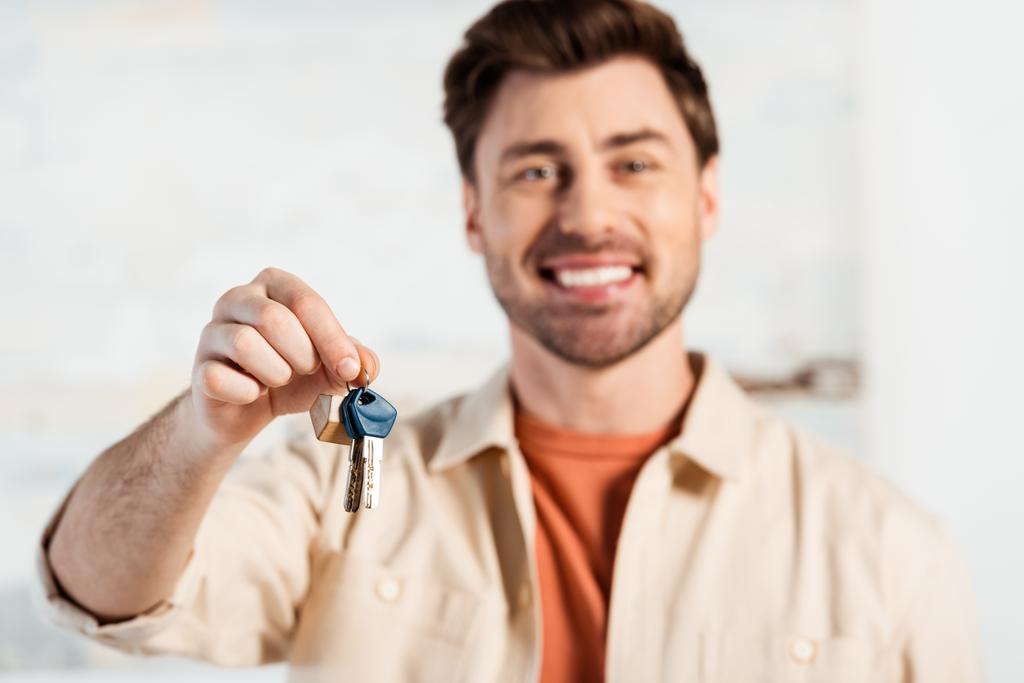 Selectieve focus van lachende man met sleutels van nieuw huis  - Foto, afbeelding