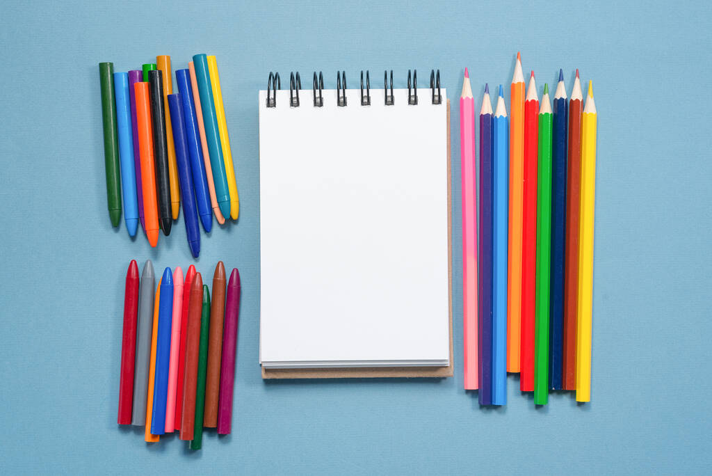 Crayons colorés et page papier vierge avec espace de copie sur fond bleu
. - Photo, image