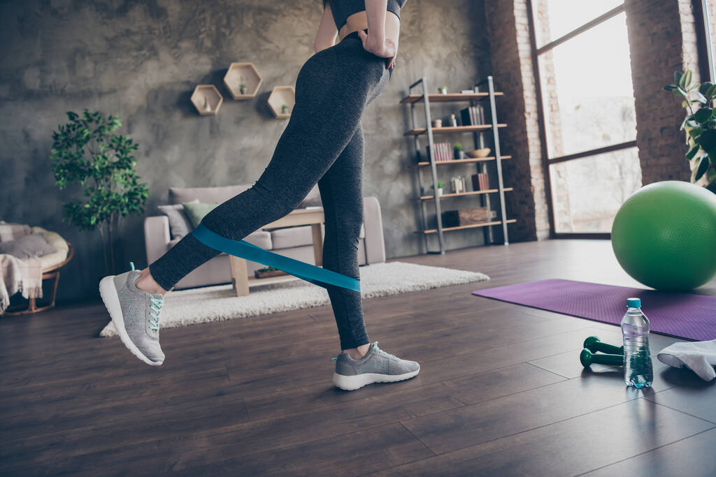 Przycięty profil boczne zdjęcie silnej sportowca robi ćwiczenia sportowe używać elastyczny ekspander nosić majtki gumowe buty w domu w domu - Zdjęcie, obraz