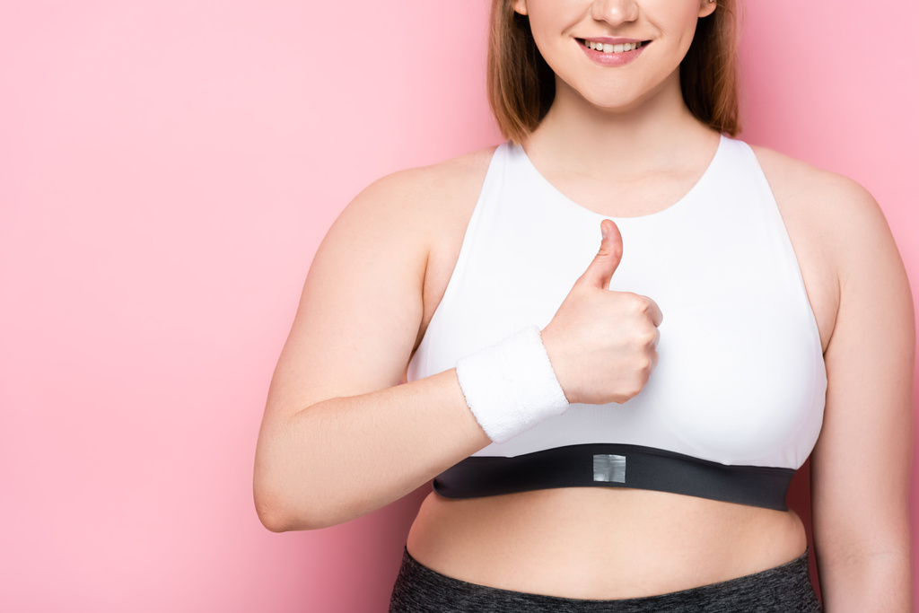 cropped view of smiling overweight girl showing thumb up on pink - Photo, Image
