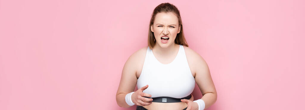 vaakasuora kuva vihainen ylipainoinen tyttö urheiluvaatteet huutaa vaaleanpunainen - Valokuva, kuva