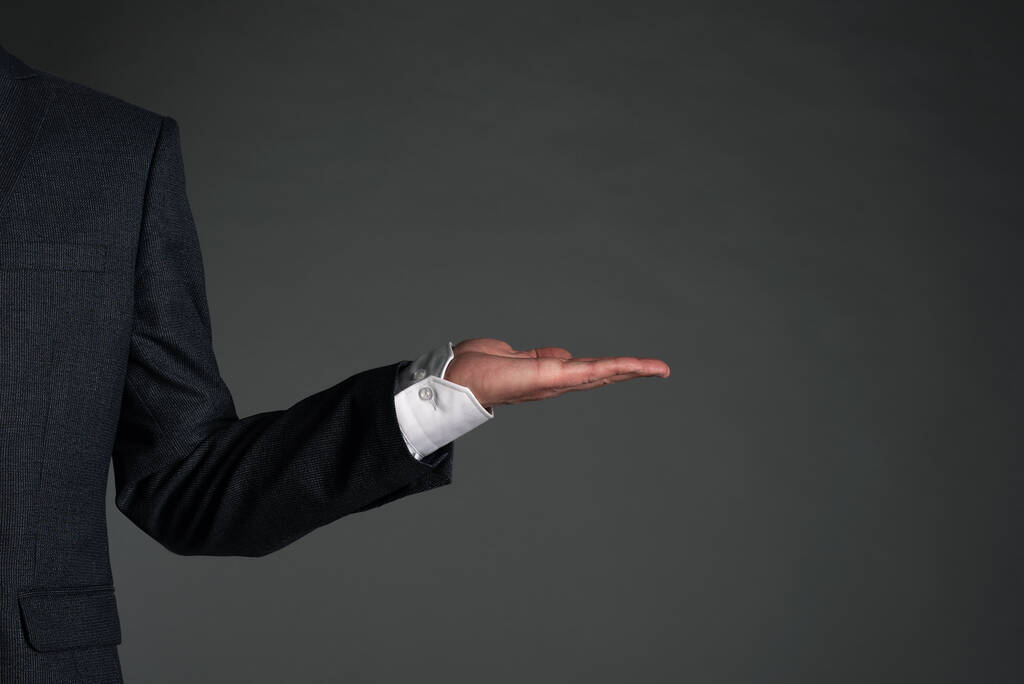 Geschäftsmann hält auf einem grauen Hintergrund einen Kopierraum in der Hand. Vorlage für Unternehmenspräsentation. - Foto, Bild