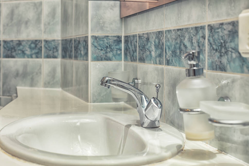 Primo piano del rubinetto moderno e lavandino in ceramica in bagno con acqua corrente
 - Foto, immagini